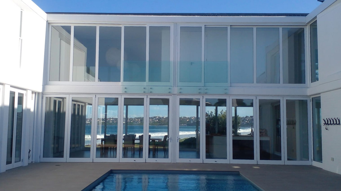 Prism Construction completed luxury modern house in St Francis Bay featuring a swimming pool, expansive glass sliding doors, and premium polished architectural finishes.